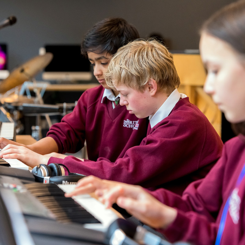 Senior students playing keyboards during music class at The British School of Amsterdam